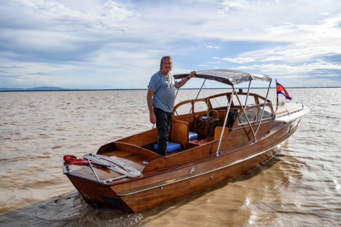 A man (James May) on a boat in the middle of the Mekong delta