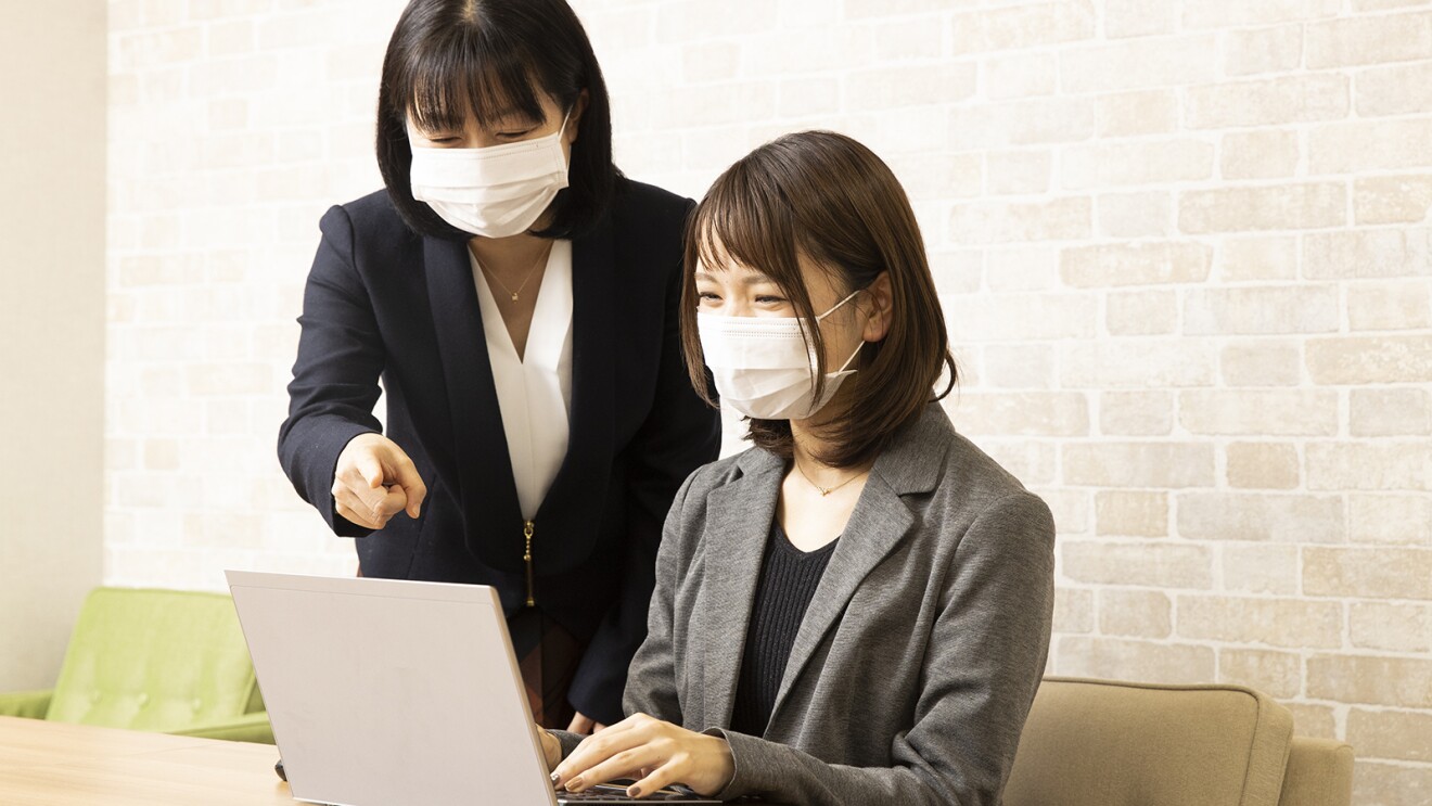 横田さんと話しつつパソコンに向かう正田さんの写真