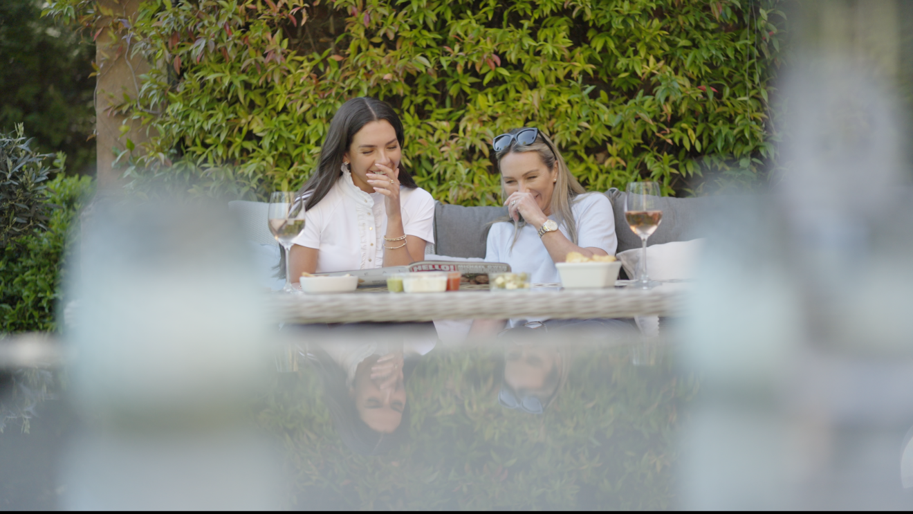 Gemma and Louise Owen laugh together, sat in a garden with a glass of rose