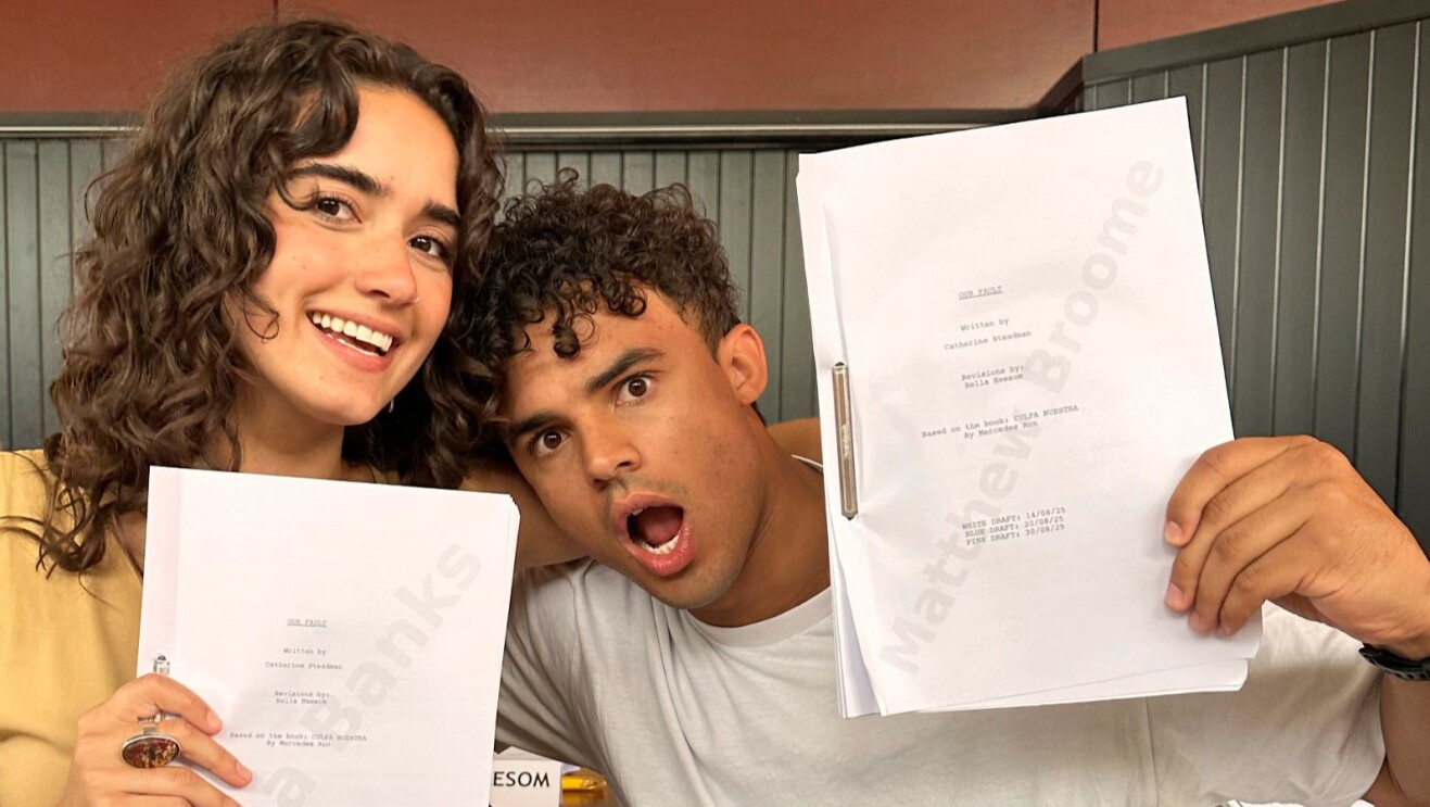 Two actors excitedly holding up script pages