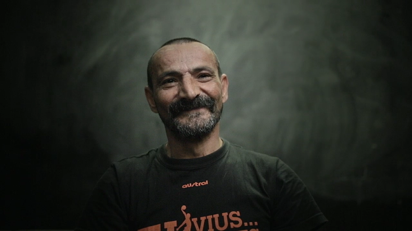 Sobre un fondo oscuro aparece sonriendo, bajo el bigote y la perilla, José Luis. 