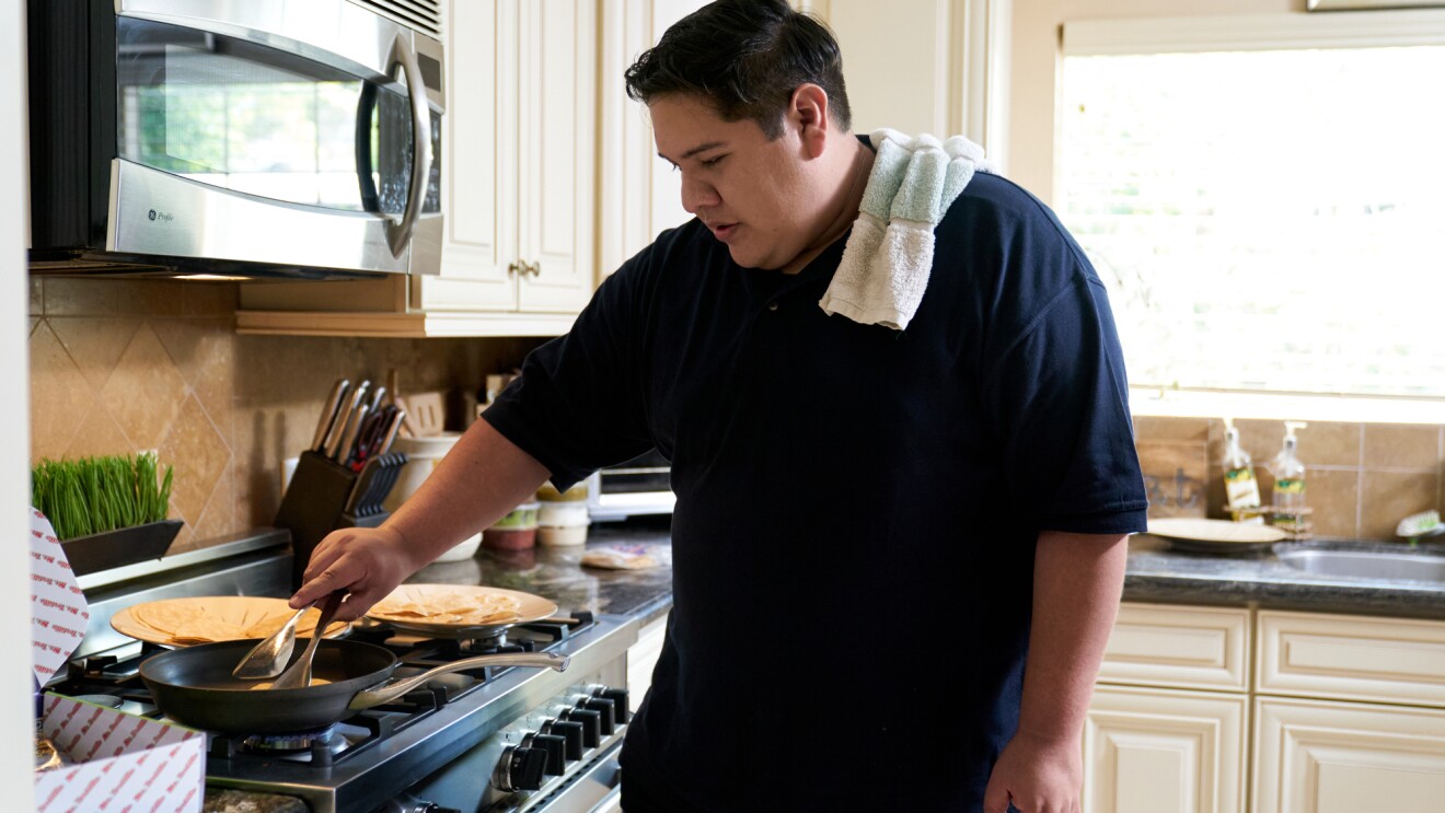 A man makes tortillas in a home kitchen.