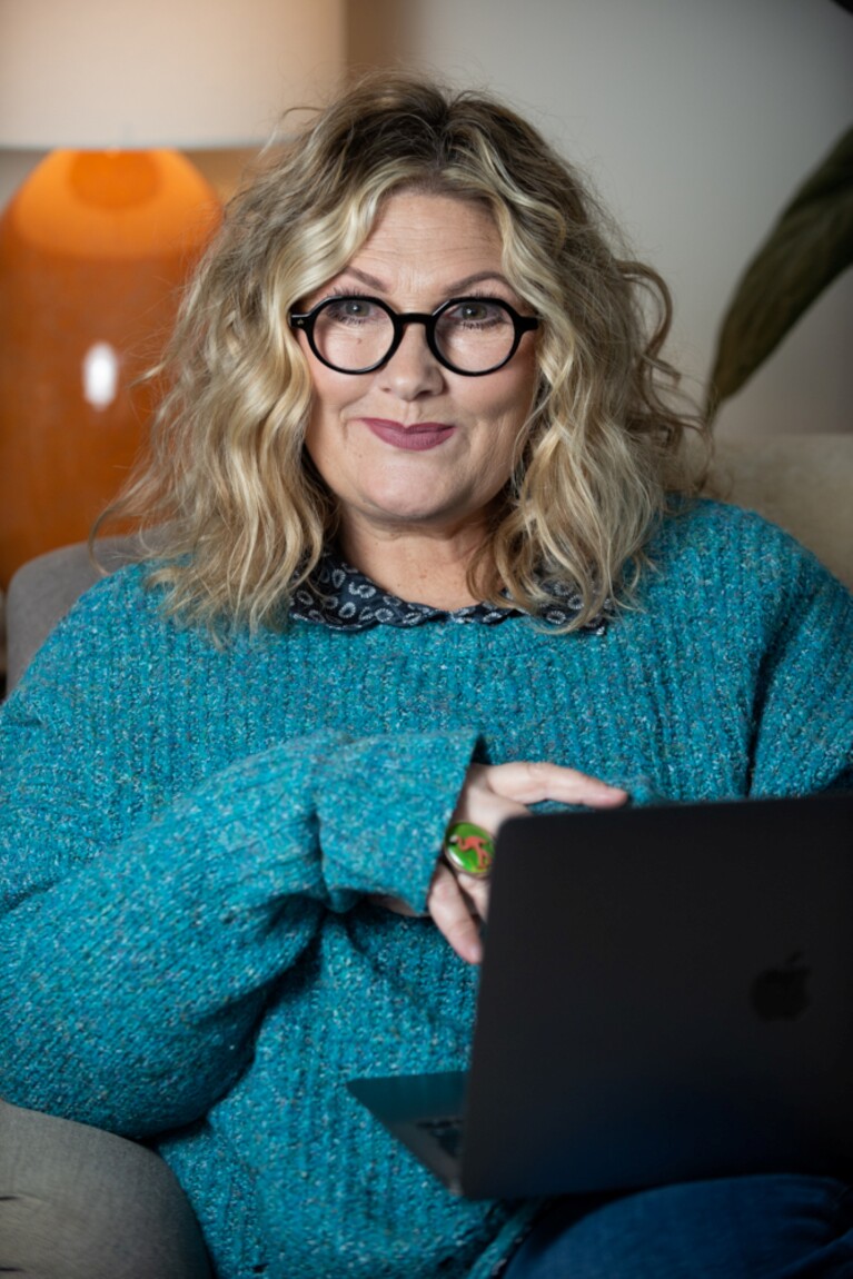 An author sitting looking at the camera holding a mug 
