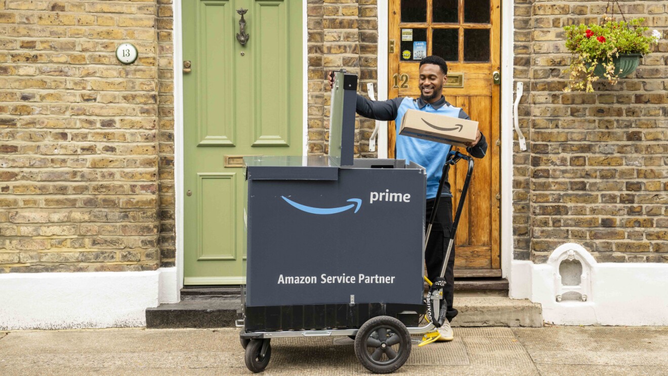 Amazon Prime delivery person smiling with package on doorstep
