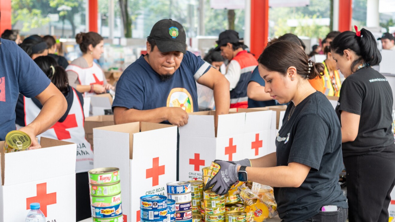 Voluntarios de Amazon encajando productos en cajas de la Cruz Roja. 