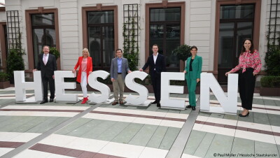 AWS-Leiter in Deutschland und Minister in Hessen stehen hinter großen Buchstaben die HESSEN legen. 