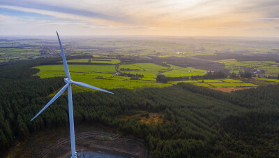 A wind turbine, from an Amazon wind farm, in front of fields in Europe. 