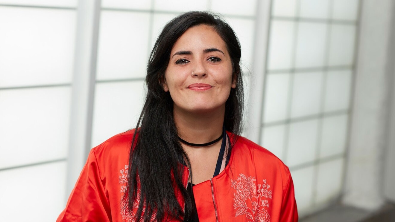 An image of Rocio wearing an orange jacket and smiling.