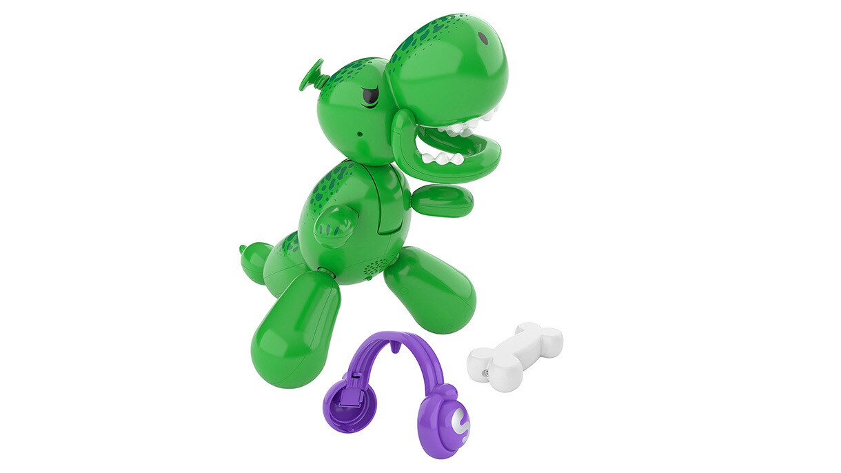 An image of the children's toy, Squeakee the Balloon Dino. It's a green dinosaur balloon animal with purple headphones and a white bone as accessories.
