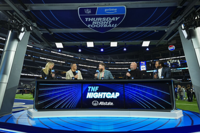 Five sports commentators talk at a blue desk following a Thursday Night Football game.