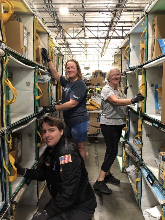 Three individuals working together in an Amazon delivery station. 