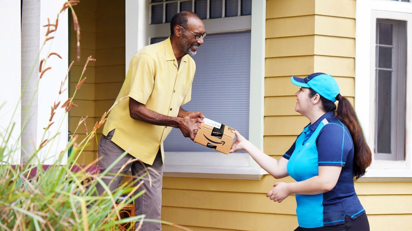 An image of an Amazon employee delivering a package to a man.