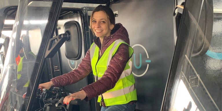 An image of Beryl Tomay smiling and in the front seat of an Amazon delivery vehicle