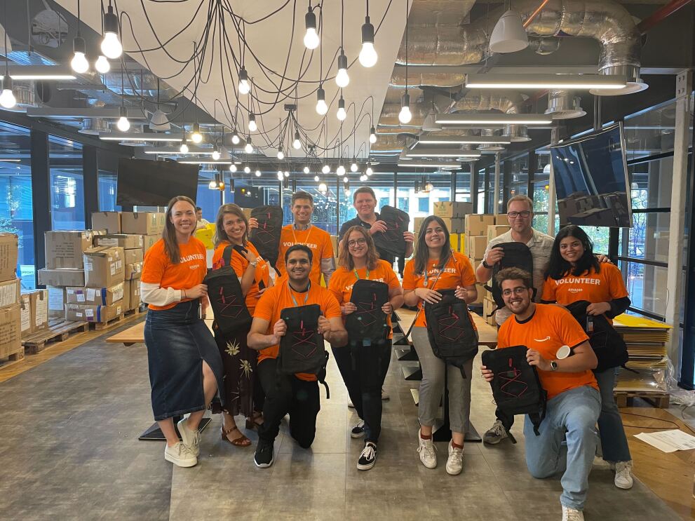 Amazon volunteers pose with backpacks donated to children ahead of the new school term