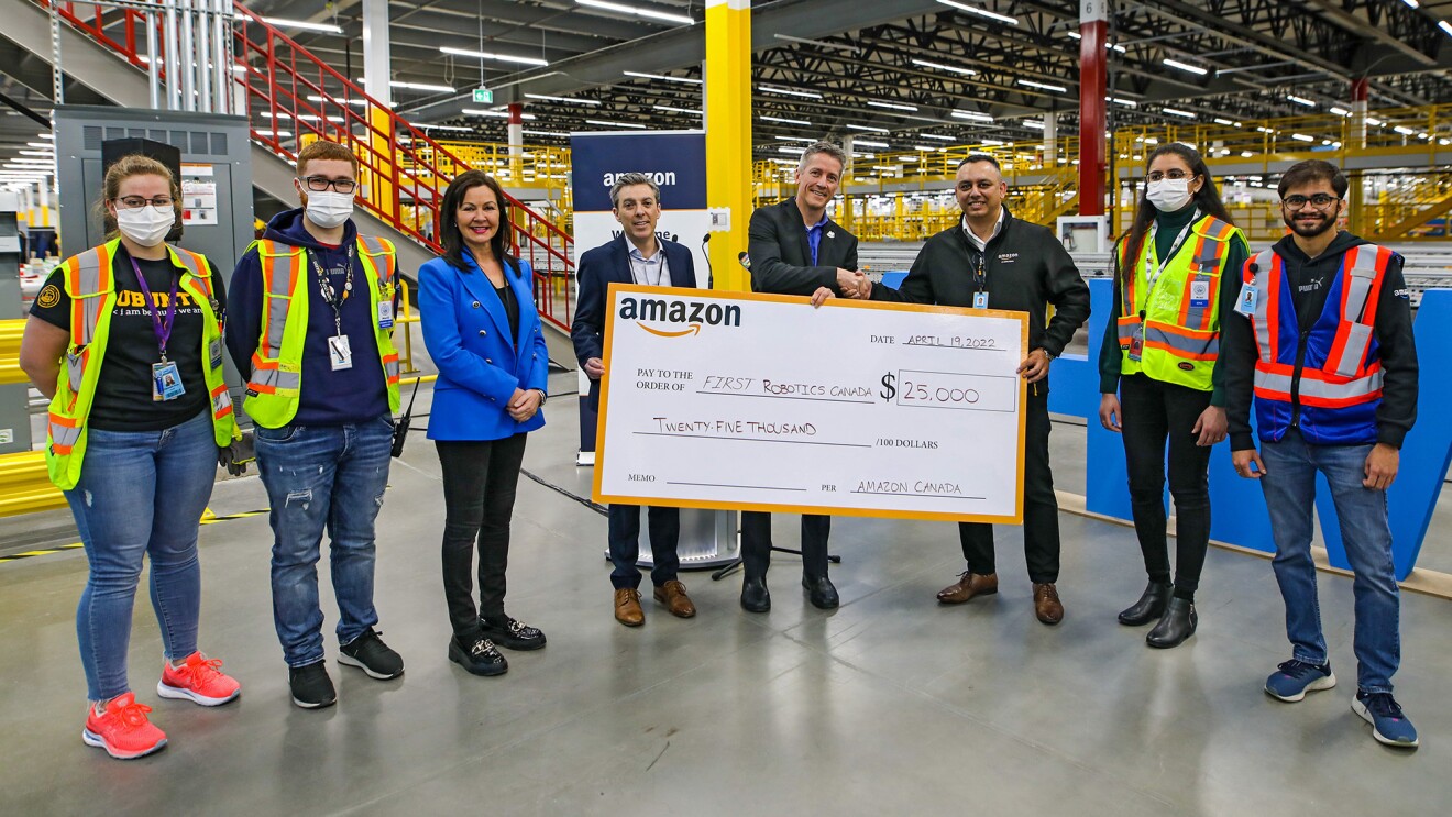 A photo of Amazon Canada employees presenting a donation of $25,000 to FIRST Robotics Canada, an organization focused on engaging young people in mentor-based programs that build STEM skills.