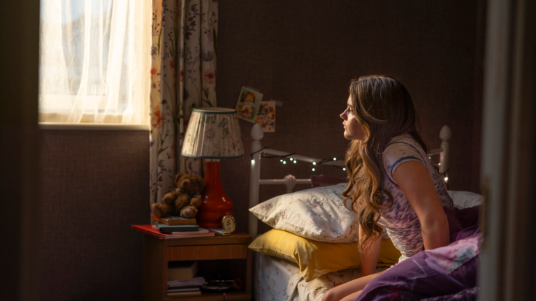 Nancy Surridge (Shannon Lynch) in Boys of Tommen sitting on a bed looking out of the window.