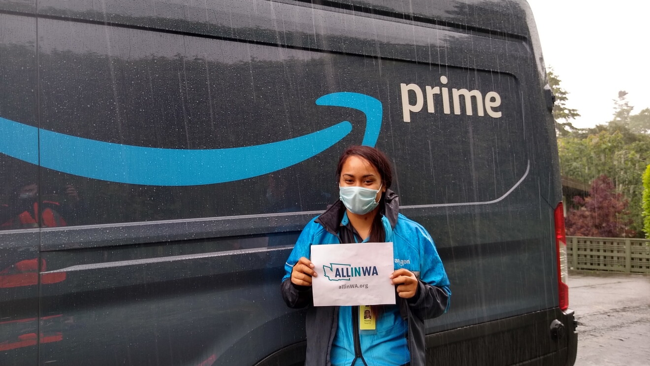 Amazon associate holds a sign that says "All in WA" 