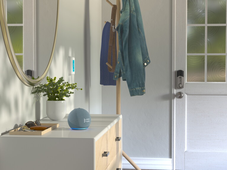 Ein Echo Dot mit Uhr auf einer Garderobe im Hauseingang.