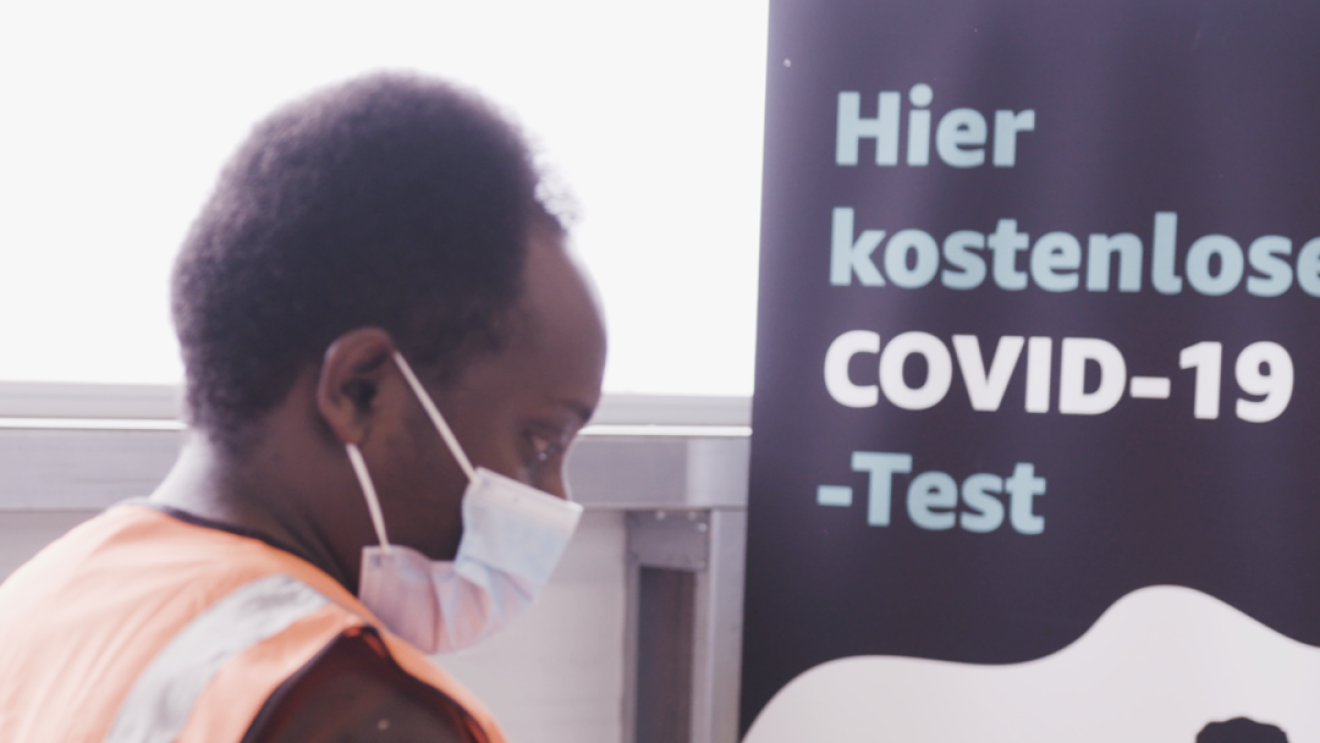 Ein Mann steht vor einem Schild auf dem steht: kostenlose Coronatest