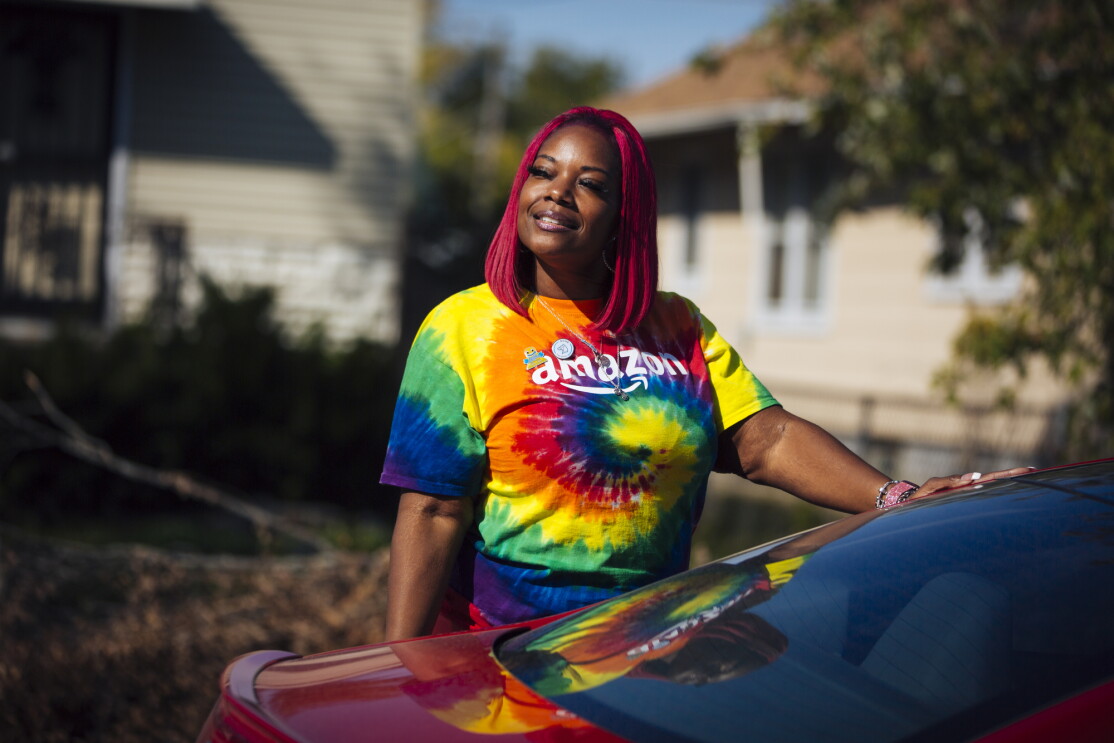 Auhzha Wright stands outside her car wearing a tie-dye shirt with the Amazon logo emblazoned across the chest.