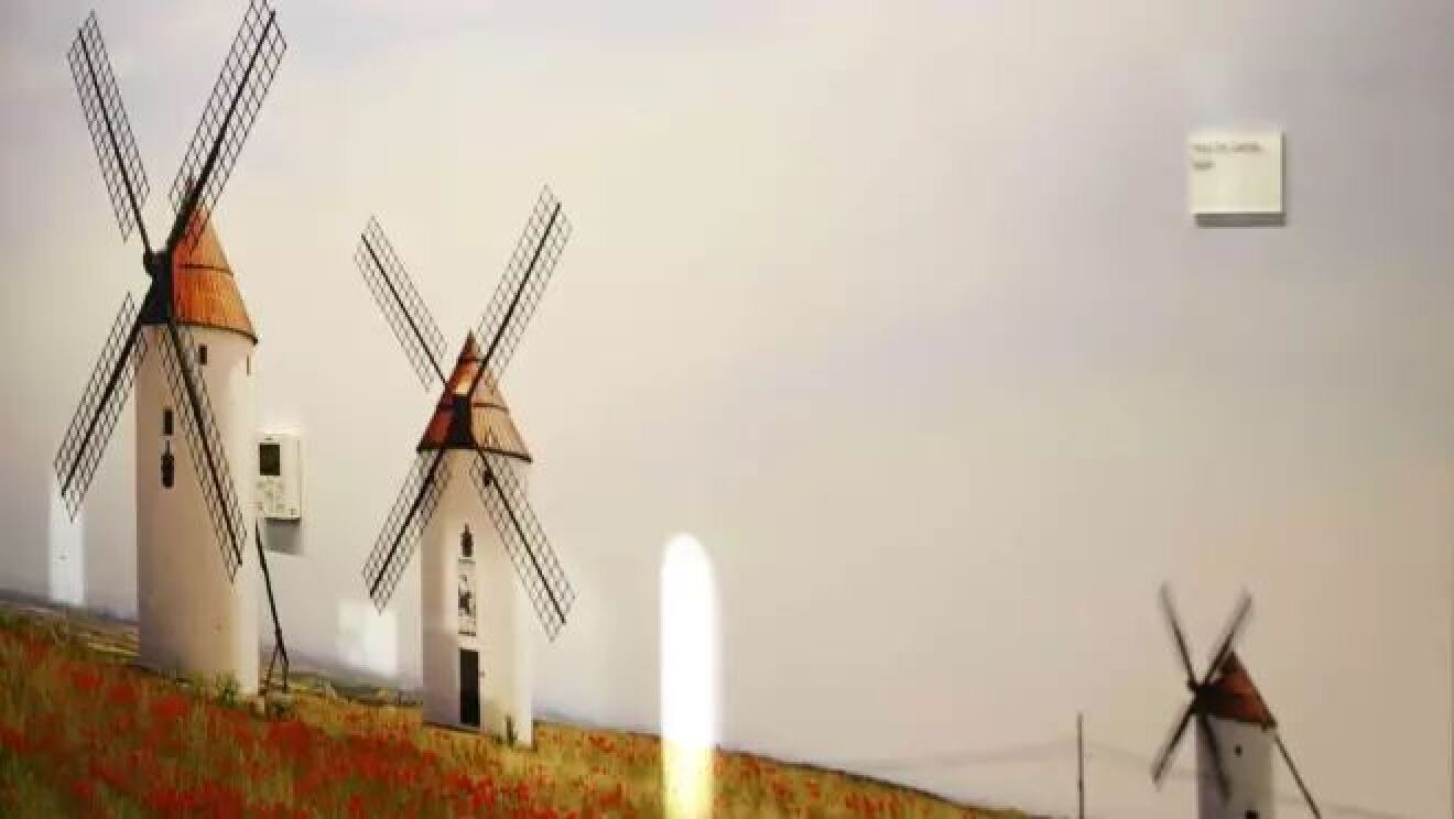 草原の真ん中に建つ3基の風車のイメージ。