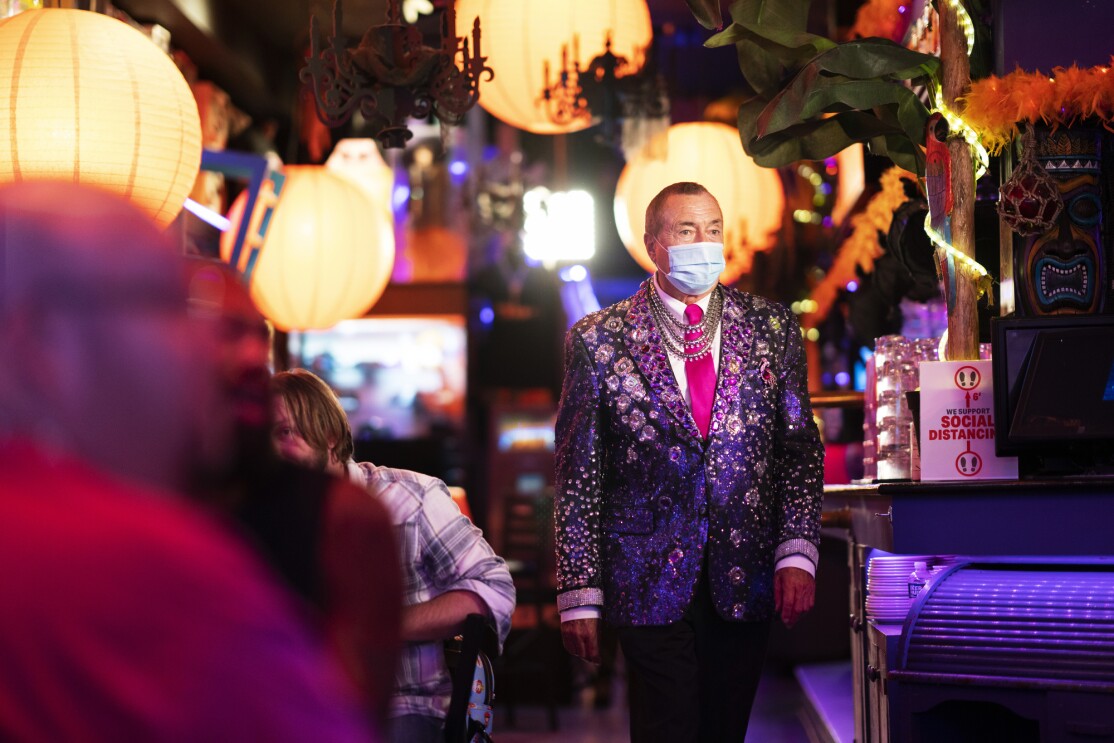 A man in a decorated purple blazer moves through a restaurant.