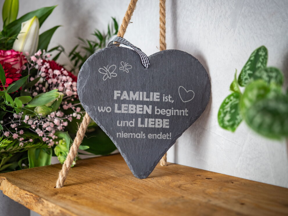 Auf einem Regal steht ein Herz aus Stein mit der Aufschrift "Familie ist, wo Leben und Lieben niemals endet".