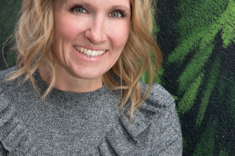 Portrait of children's book author, Rebekah Crane. She's wearing a long-sleeve gray sweater with a ruffled yoke and loosely curled hair
