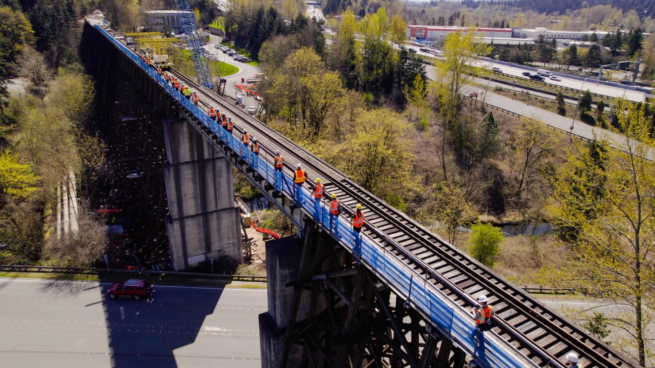 Amazon volunteers with community city volunteers walking across a train bridge.