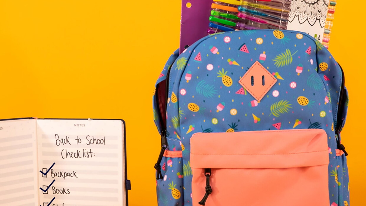A brightly colored backpack filled with pens, a folder, and more, sits in front of a yellow background. To the right is a notepad that has writing on it that says "Back to school checklist, backpack, books, stationary, lunchbox" 