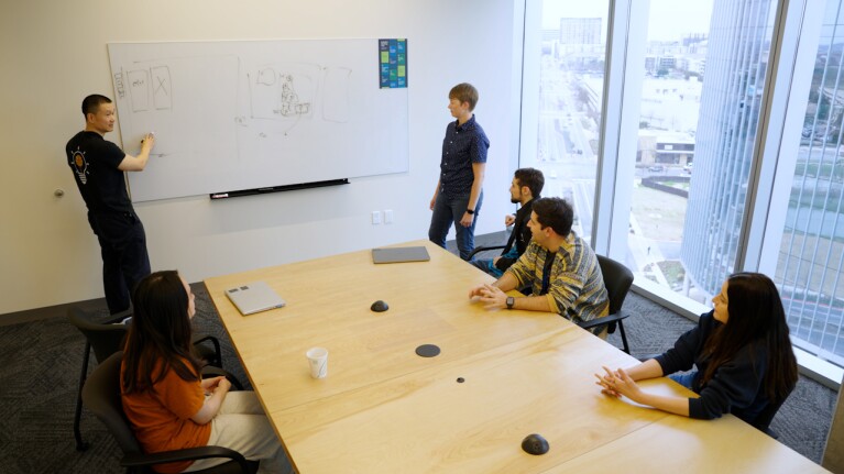 Team collaborating in modern office meeting room with whiteboard