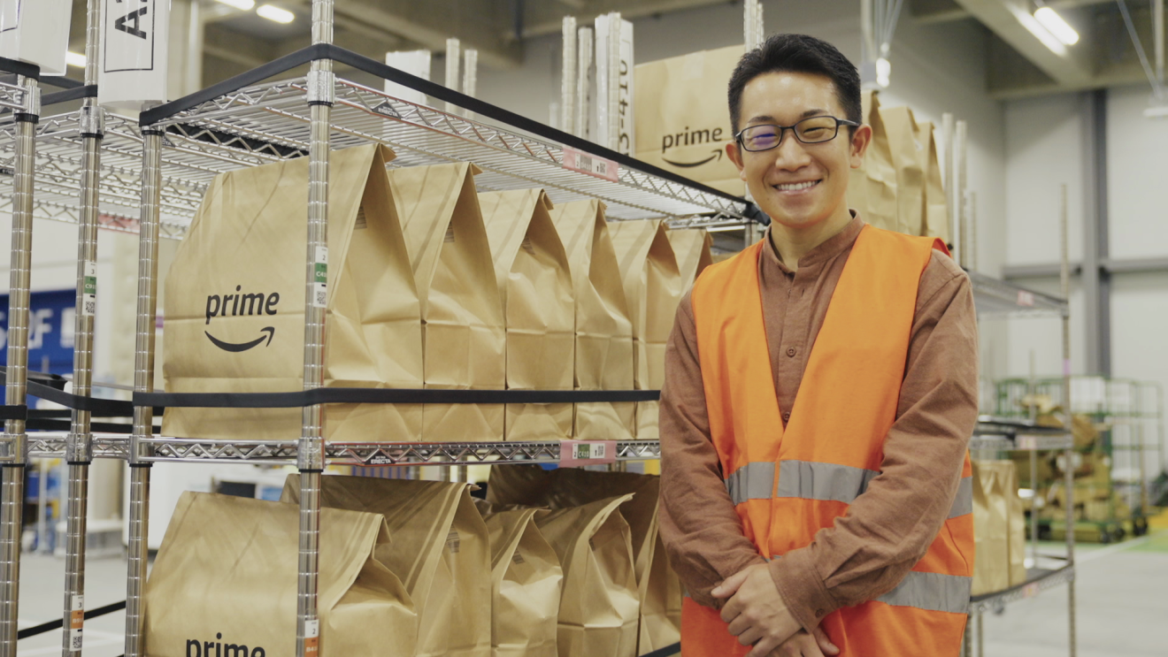 Amazonフレッシュの紙袋の前に立つ笑顔の大山良さん