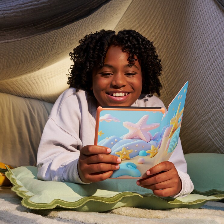 A young girl smiling while reading her Kindle Paperwhite Kids