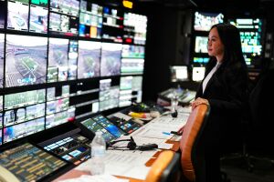 Woman looks at a gallery of monitors during Thursday Night Football