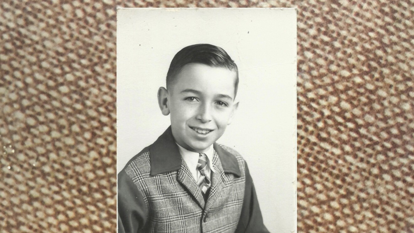 Rick Reefer at age 10. It's a black and white photograph and he is smiling and wearing a tweed jacket.
