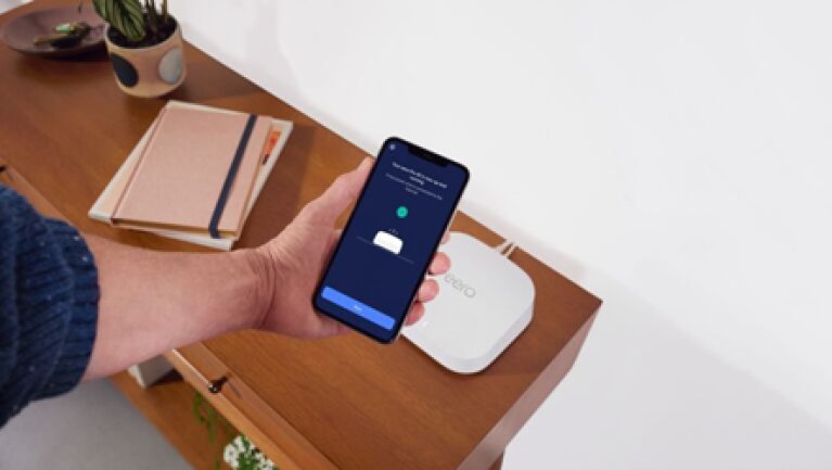 Somebody holds up their phone to connect to an eero device
