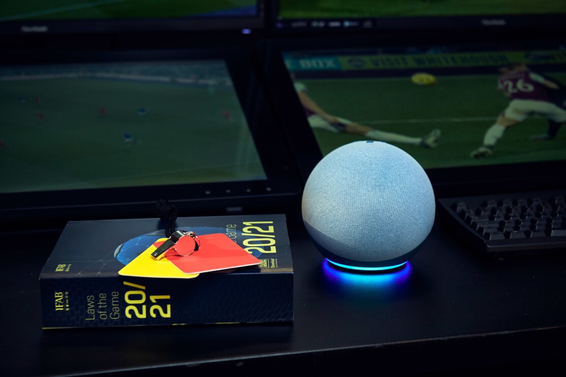 The Echo Dot on a table with a book of football rules and a red and yellow card