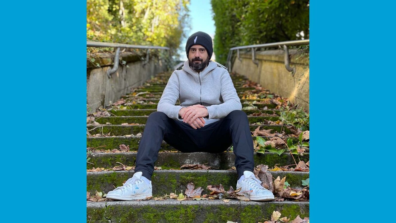 David sitting outside on stairs covered with leaves.