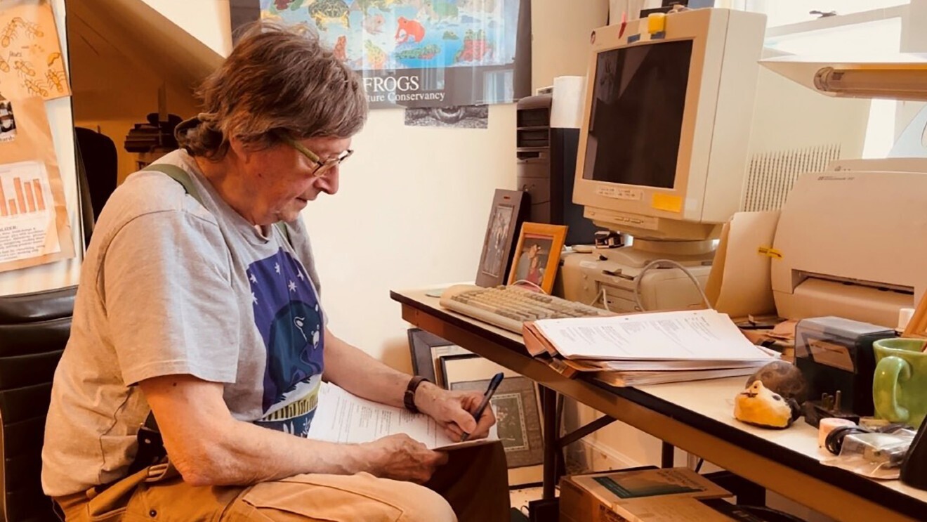 A photo of author Lloyd Devereux Richards writing at his desk.