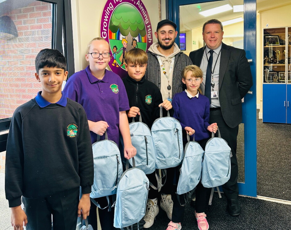 Children and teacher pose with backpacks donated by Amazon volunteers