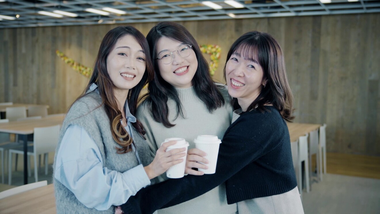 3人の女性は、ペーパーカップを持ちながら仲良さそうに笑っている