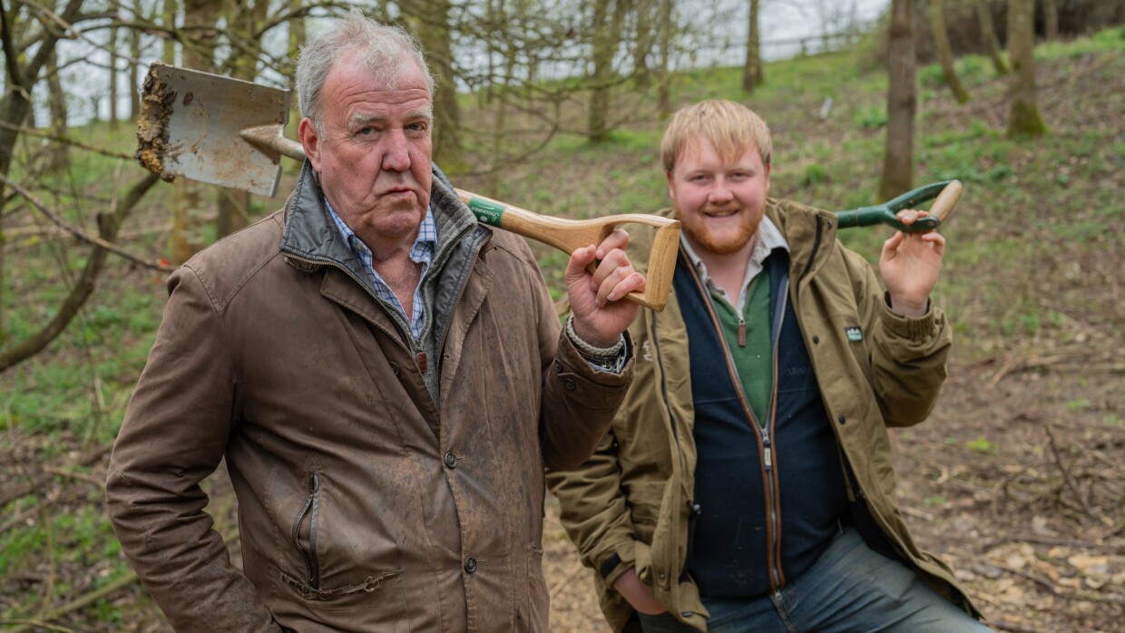 Jeremy Clarkson and Kaleb Cooper standing in the woods holding shovels 