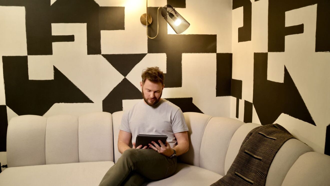 Bobby Berk using tablet on modern couch with geometric wall art