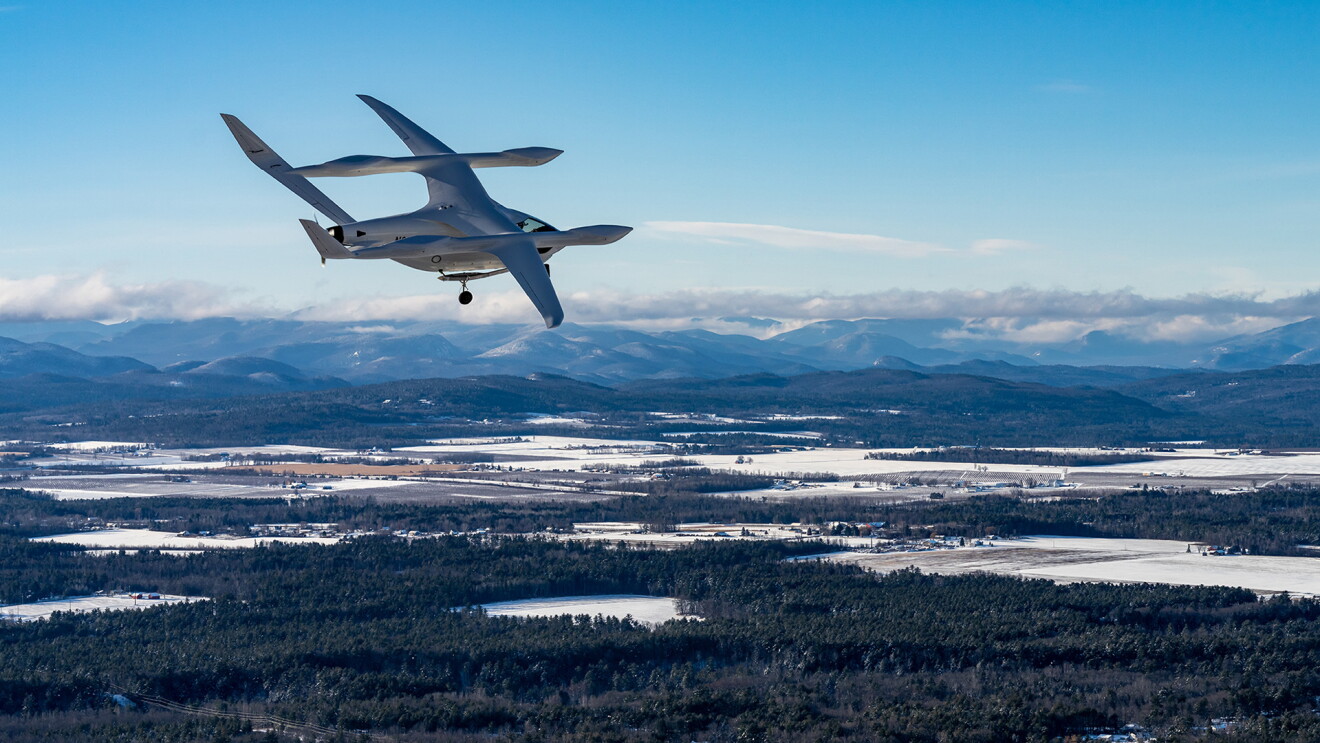 Ein klimaneutrales Flugzeug von BETA Technologies fliegt über einer Winterlandschaft.