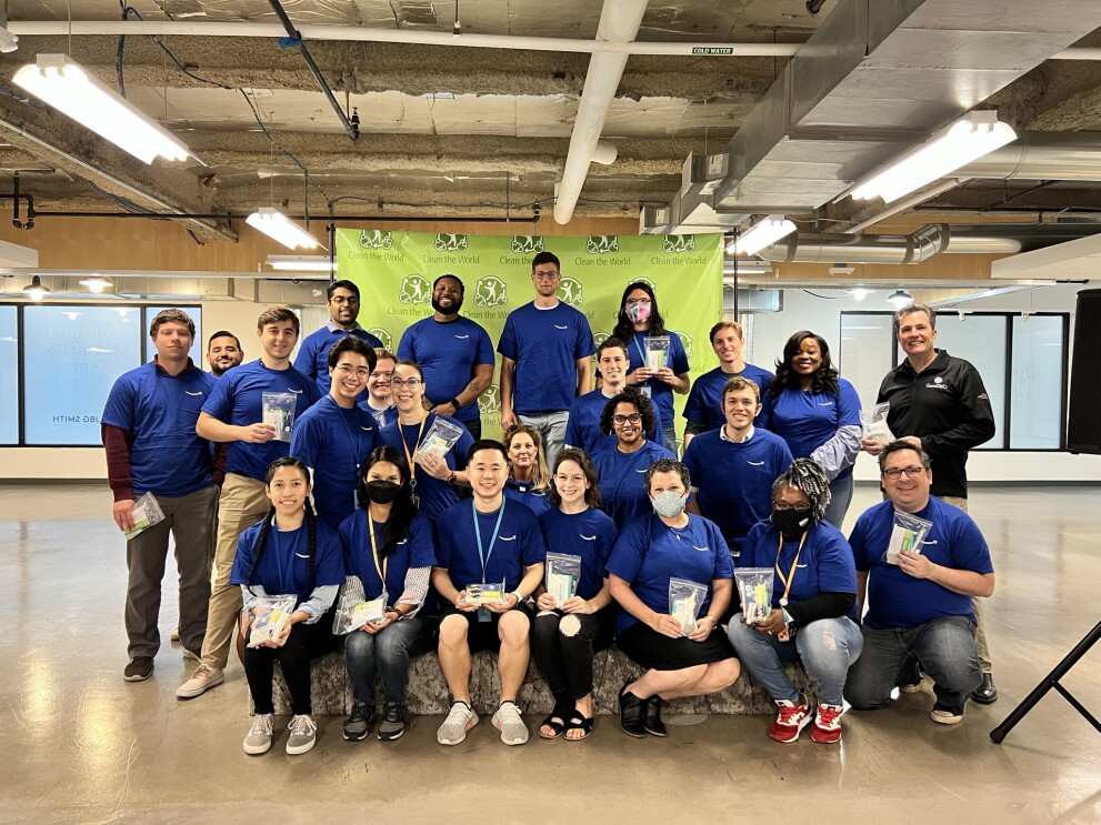 A group of Amazon employees wear blue Amazon T-shirts and hold hygiene packs to be sent to Ukraine.