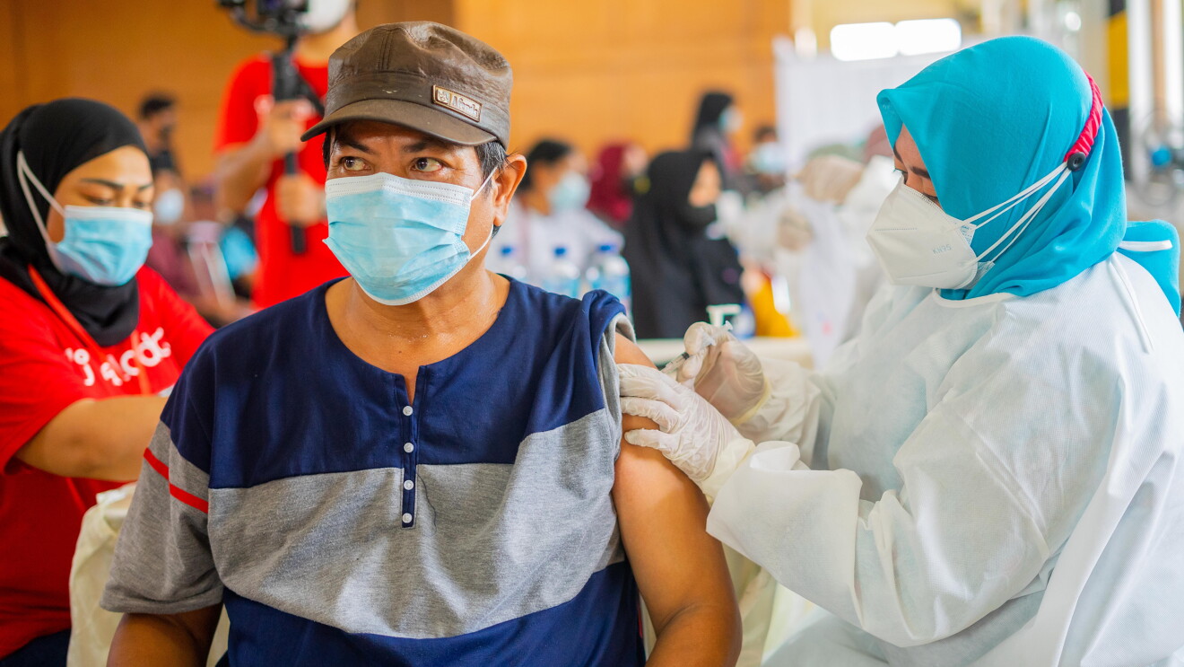 An Indonesian man is being vaccinated by a nurse in a vaccination centre