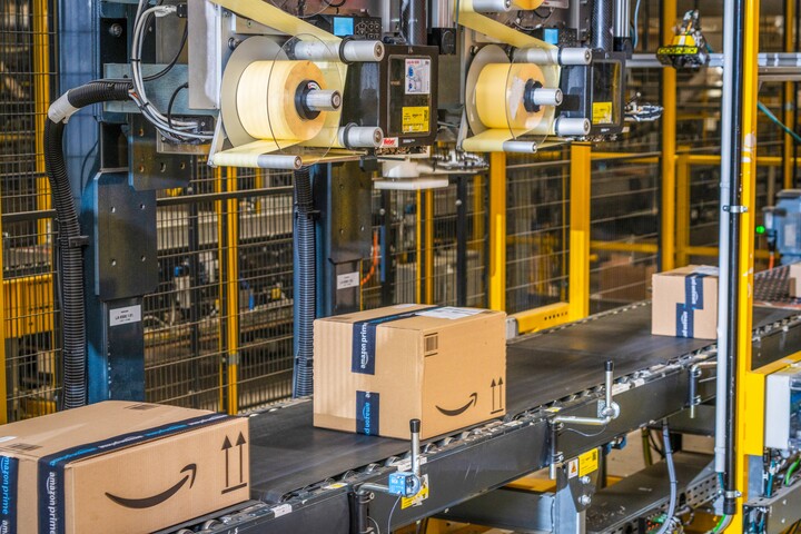 Colis Amazon transportés par convoyeur automatique dans un centre de distribution