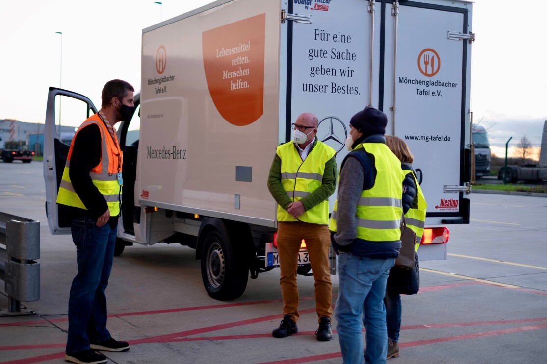 Mitarbeiter von Amazon und der Tafel vor einem Tafel-Lieferwagen.