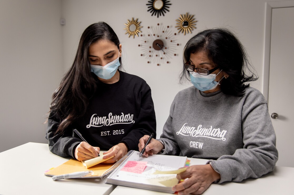 Two women take notes in a workplace.