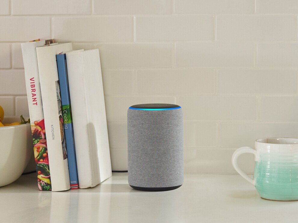 Echo device in a kitchen. To the left are cookbooks, to the right is a stoneware mug that fades from aqua to white. 